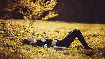 Young woman relaxing on grass in golden hour light