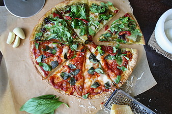 Flat lay of two sliced pizzas with fresh basil and garlic