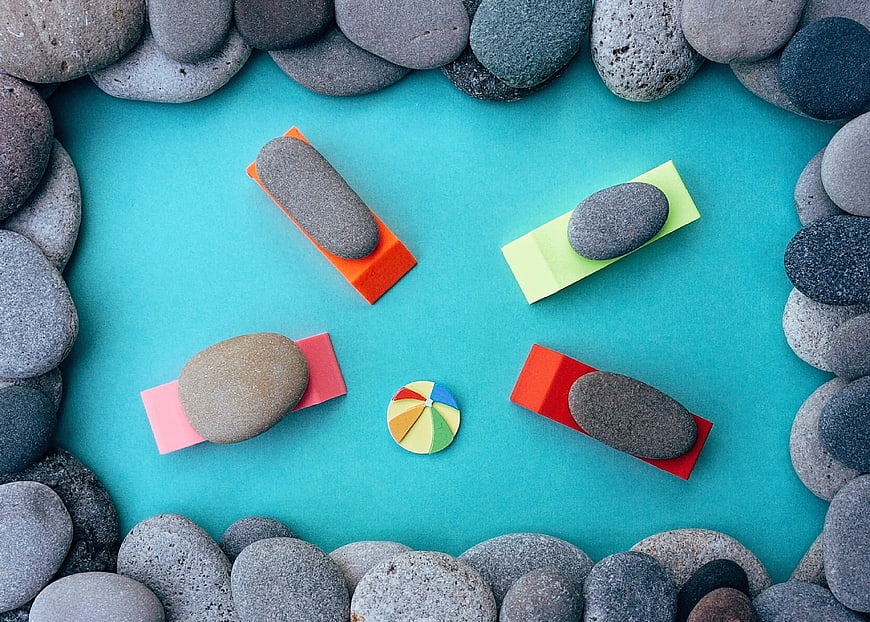 Flat lay of smooth stones on colorful sticky notes with umbrella
