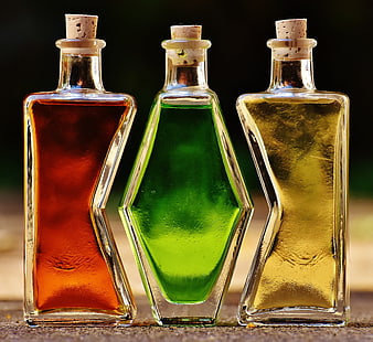 Three Colorful Glass Bottles with Corks on Wooden Surface
