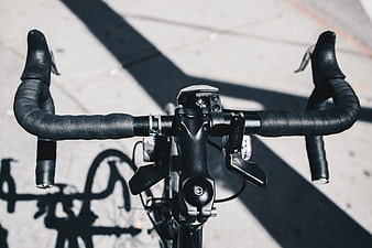 Close-up of black road bike handlebars on pavement