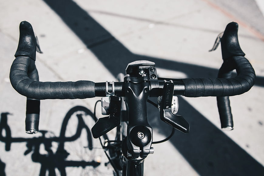 Close-up of black road bike handlebars on pavement