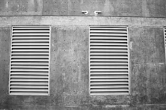 Black and white concrete wall with ventilation grilles