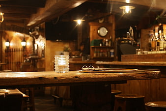 Cozy rustic wooden bar counter with candle and menu in dimly lit pub