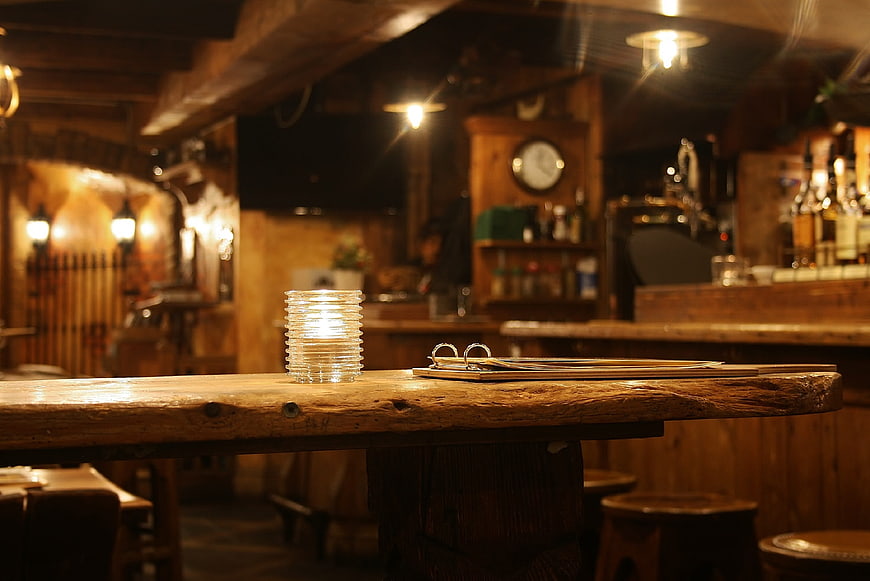 Cozy rustic wooden bar counter with candle and menu in dimly lit pub