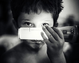 Close-up of boy holding flashlight to face in black and white