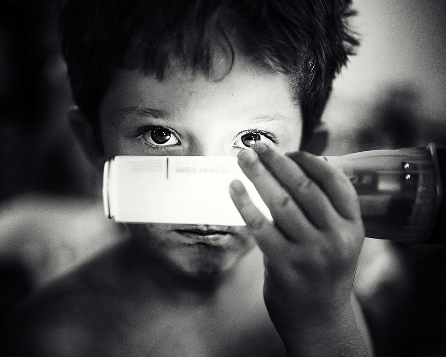 Close-up of boy holding flashlight to face in black and white