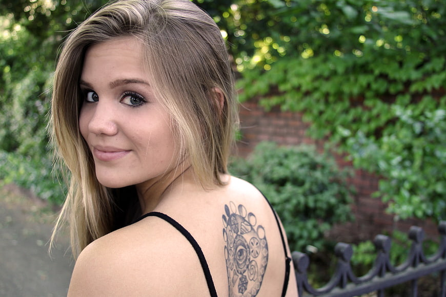 Young Blonde Woman with Back Tattoo Looking Over Shoulder