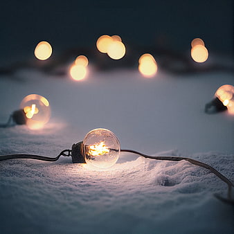 Glowing Christmas Light Bulb in Snow at Night