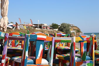Colorful Painted Wooden Chairs at a Sunny Beachside Cafe