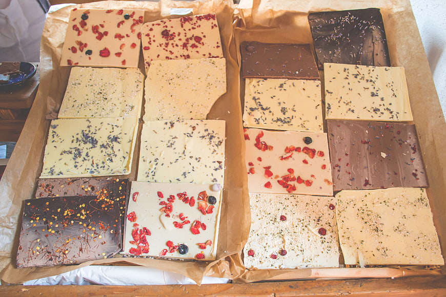 Artisanal chocolate bars with dried fruit and herbs on parchment paper