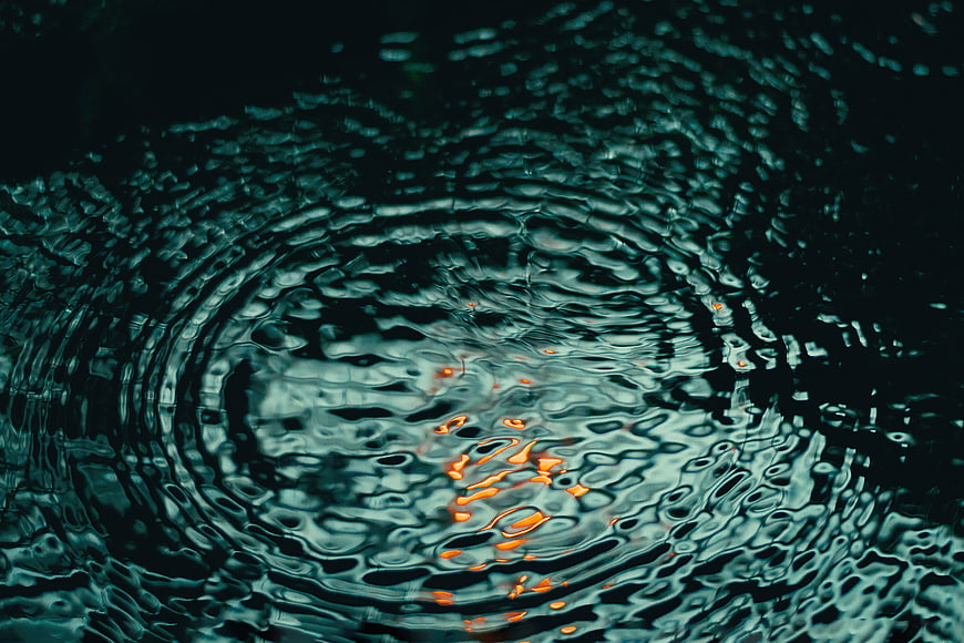 Dark water ripples with orange light reflection