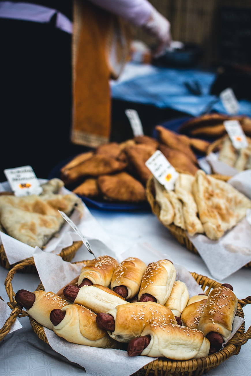 Fresh sausage rolls and pastries in wicker baskets at a market