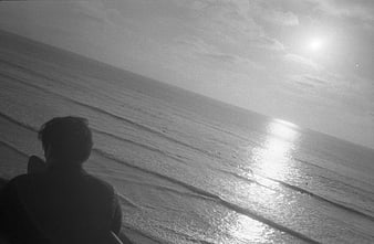 Silhouette of person looking at ocean horizon in black and white