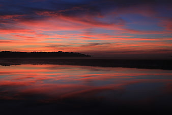 Vibrant Sunrise Reflection on Calm River with Silhouette