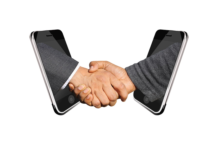 Conceptual handshake emerging from two smartphones on white background