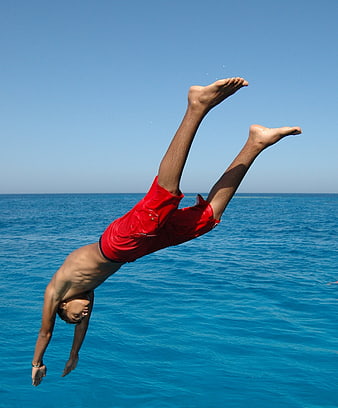 Man diving into blue ocean water mid-air