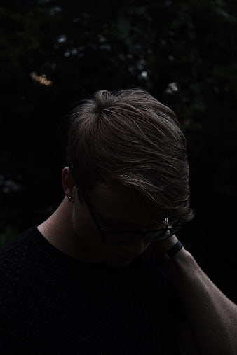 Moody Portrait of Young Man with Glasses Looking Down