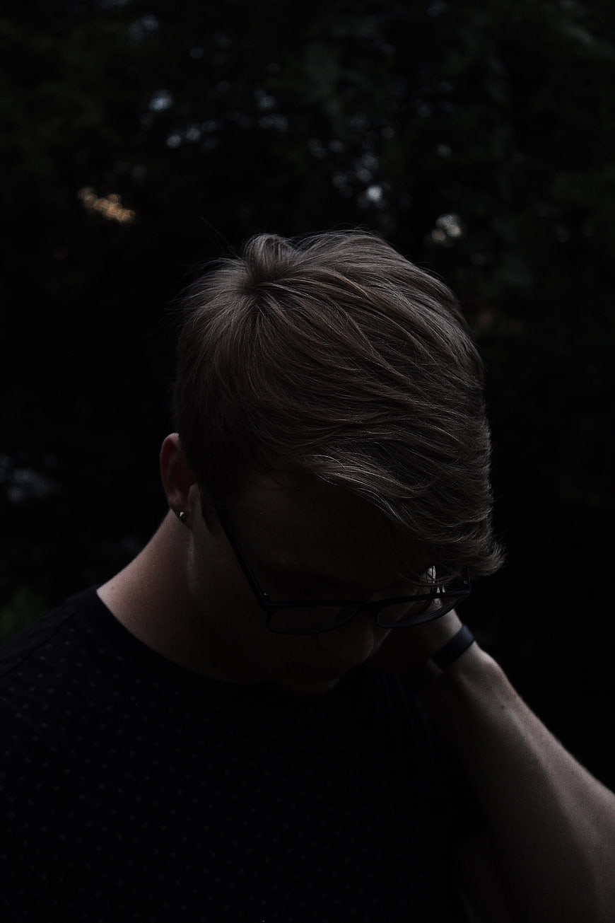 Moody Portrait of Young Man with Glasses Looking Down
