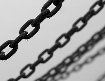 Black and white close-up of wet metal chains with water droplets