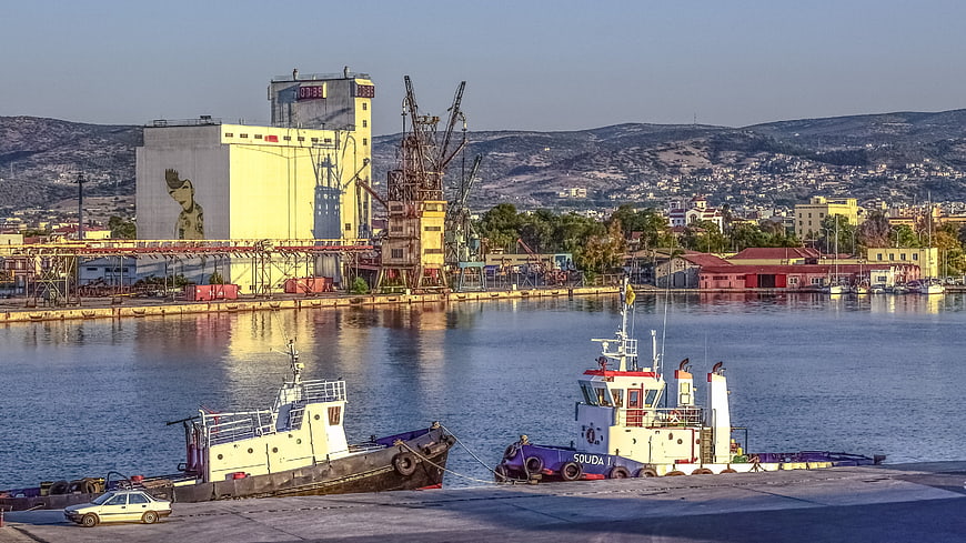 Tugboats docked at industrial port with cranes and silos