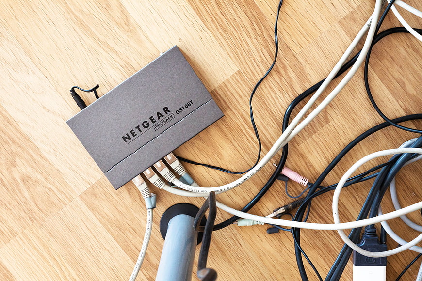 Netgear ProSAFE GS108T Switch With Tangled Ethernet Cables On Wood