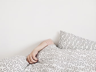 Minimalist Sleeping Person Under Patterned Bedding
