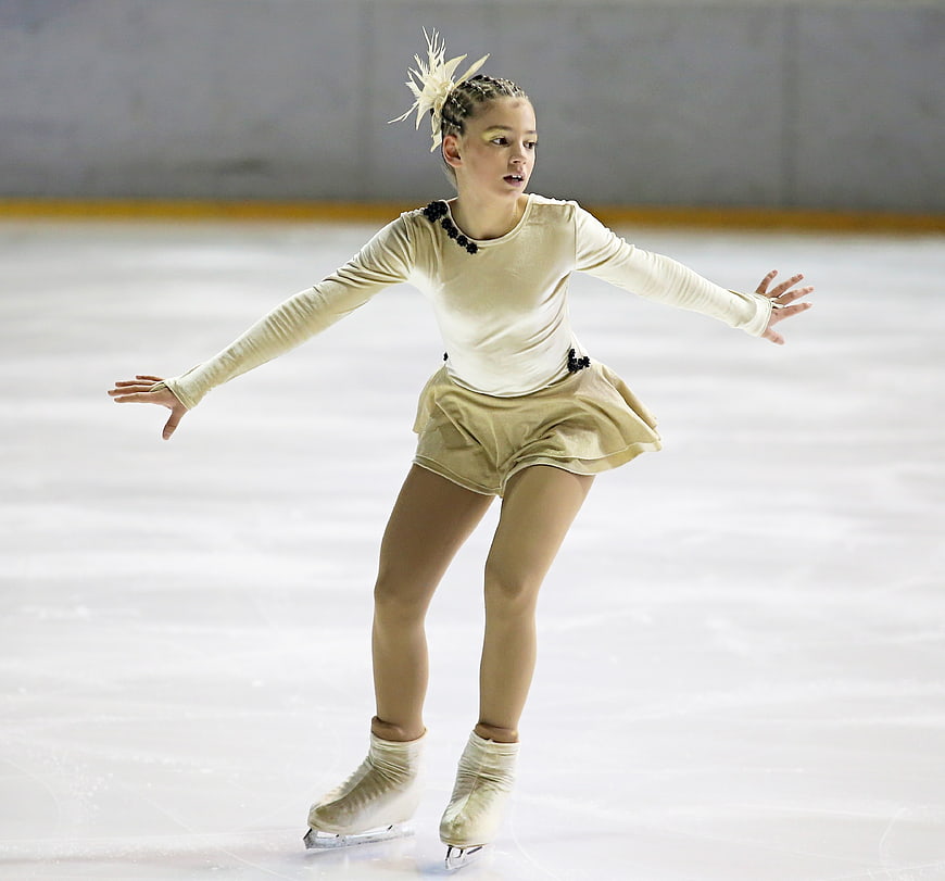 Young female figure skater performing on ice rink