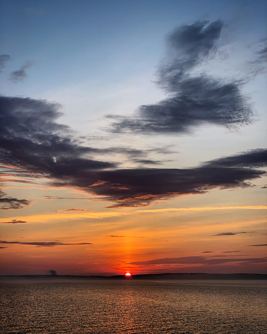 Dramatic Sunset Over Ocean with Dark Clouds and Golden Horizon