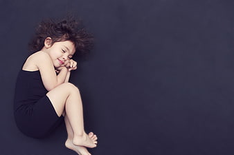 Sleeping child girl curled up on dark background
