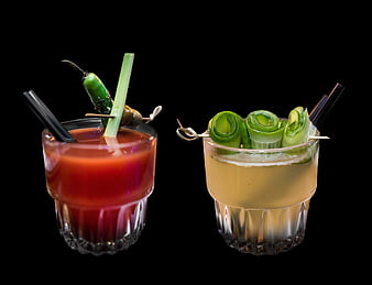 Two garnished cocktails in short glasses on a black background