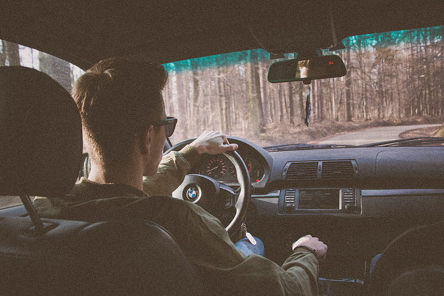 Man driving car through forest road