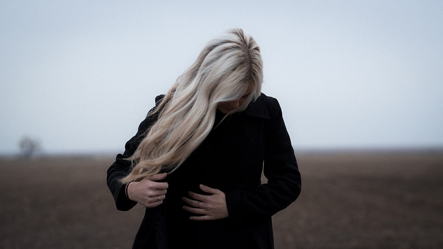 Melancholic Woman in Black Coat Standing in Foggy Field