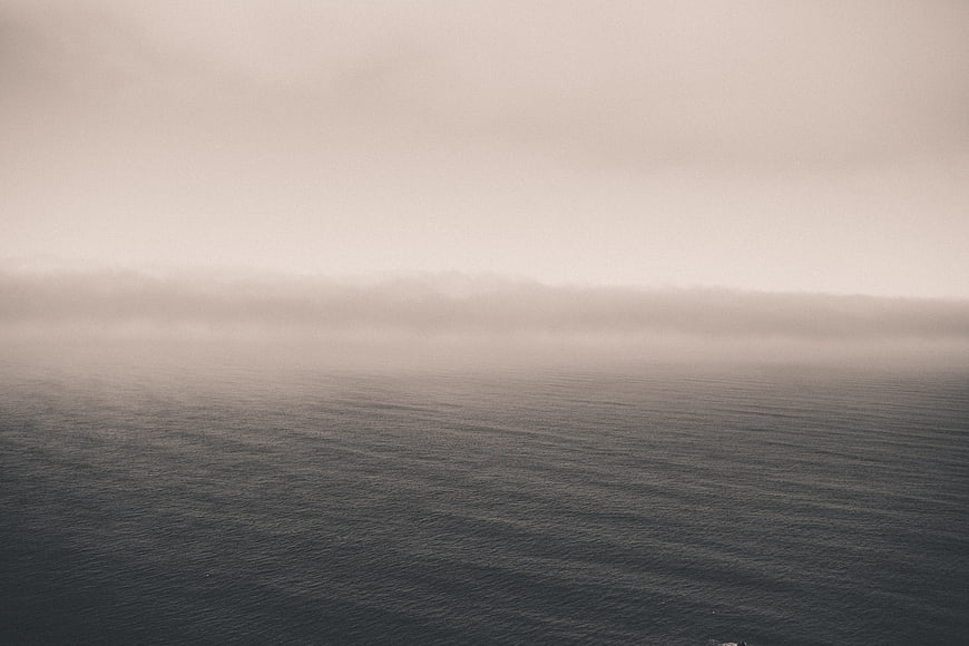 Minimalist foggy ocean horizon with calm water ripples