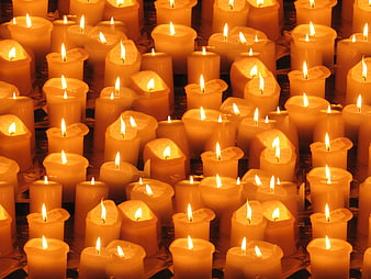Close-up of many lit yellow votive candles in a church