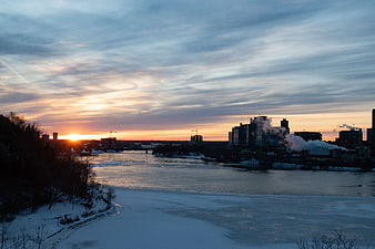 Winter Sunrise Over Frozen River and City Skyline