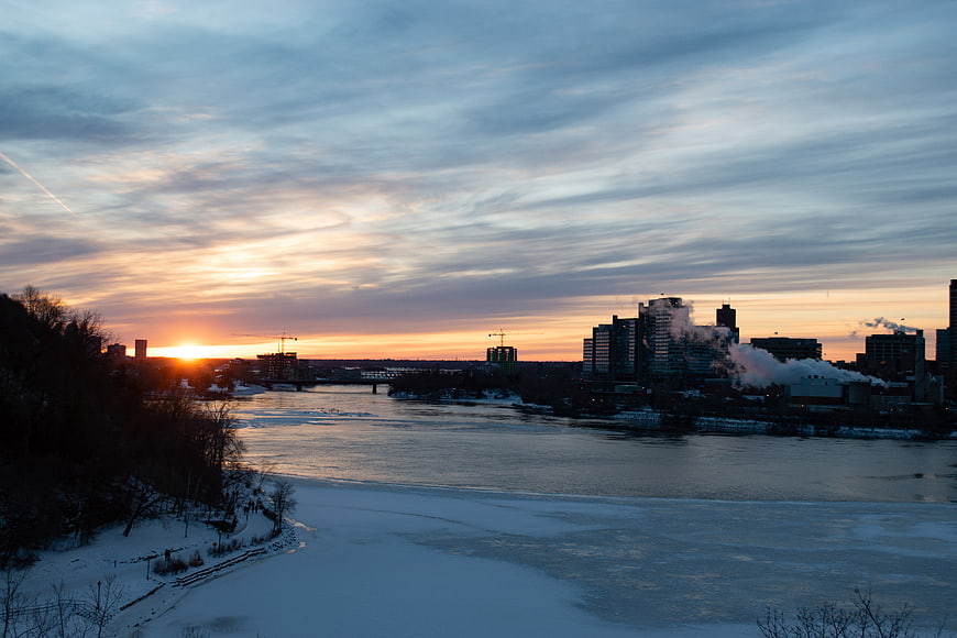 Winter Sunrise Over Frozen River and City Skyline