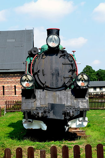 Front view of vintage green steam locomotive on tracks