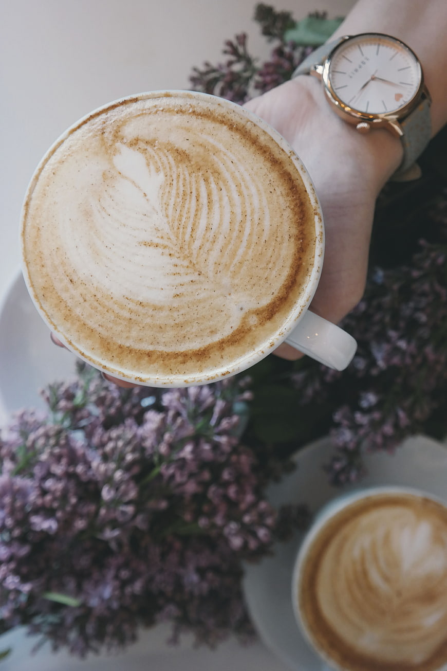 Overhead view of latte art coffee with lilac flowers