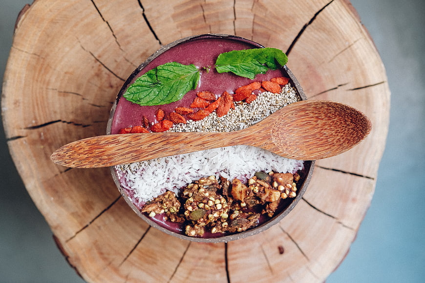Overhead view of a healthy acai bowl with granola, coconut, and mint