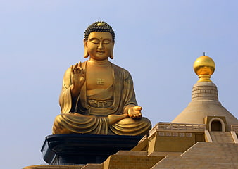 Golden Buddha Statue Seated on Pedestal Against Clear Blue Sky