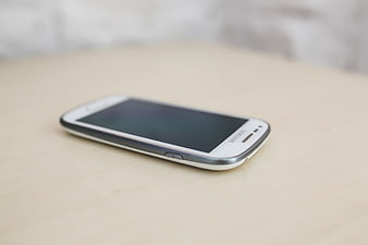 White Samsung smartphone on light wooden table