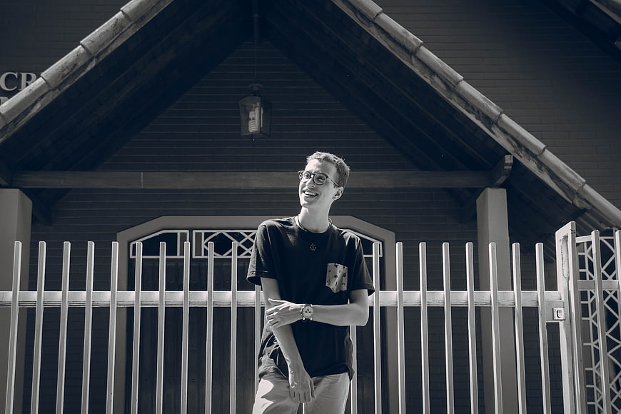 Young man with glasses smiling in front of a church