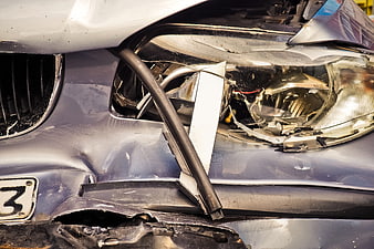 Close-up of a damaged car front bumper and shattered headlight