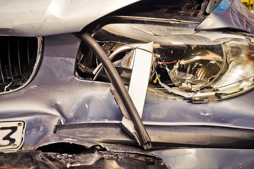 Close-up of a damaged car front bumper and shattered headlight