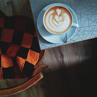 Overhead view of cappuccino with latte art on cafe table