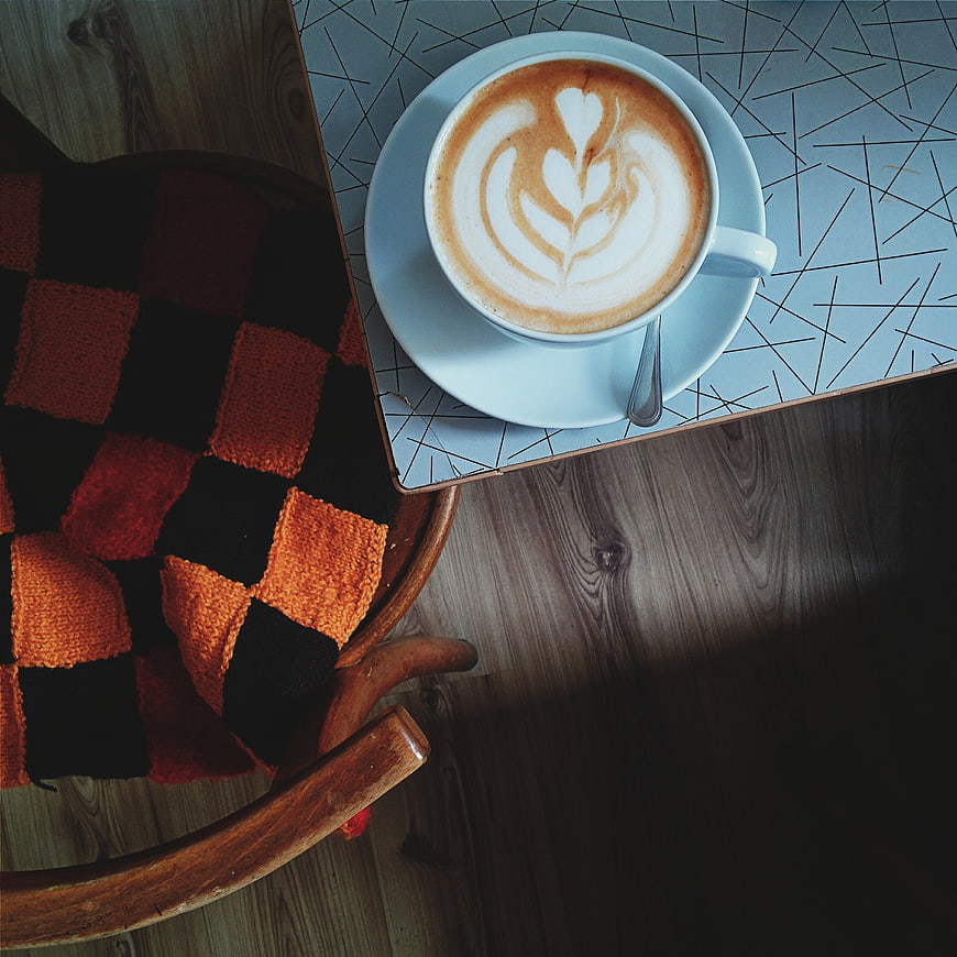 Overhead view of cappuccino with latte art on cafe table