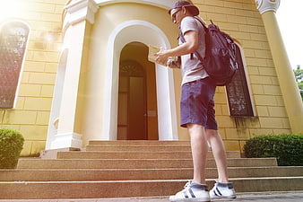 Young male tourist reading map in front of yellow building