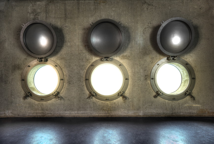 Three round porthole windows on a concrete wall