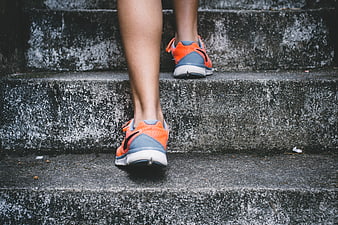 Runner's legs climbing concrete stairs in orange sneakers
